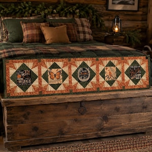May include: A rectangular quilted bed runner featuring five square panels with alternating orange, cream, and dark green geometric star patterns. The panels display a butterfly, a bird, and text reading Find Joy in Things, Choose Happy, and Pray for a Beautiful Life.