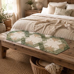 May include: A rectangular table runner featuring a quilted pattern with alternating cream-colored star shapes and dark green floral fabric sections. The design includes embroidered golden-brown menorah motifs centered within the cream star panels.