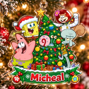 May include: A clear acrylic Christmas ornament featuring SpongeBob SquarePants, Patrick Star, Sandy Cheeks, Squidward Tentacles, and Gary the Snail decorating a Christmas tree. The name Micheal is printed in red letters on a green banner at the bottom.
