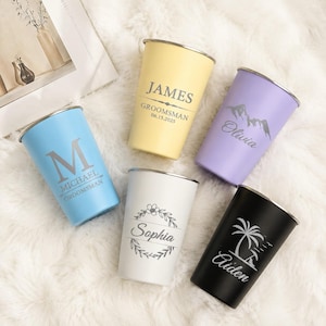 Op de afbeelding: Vijf roestvrijstalen bekers in lichtblauw, geel, lavendel, wit en zwart. Elke beker heeft een zilveren rand en aangepaste lasergegraveerde ontwerpen met namen zoals James, Olivia, Michael, Sophia en Aiden, plus diverse grafische afbeeldingen.