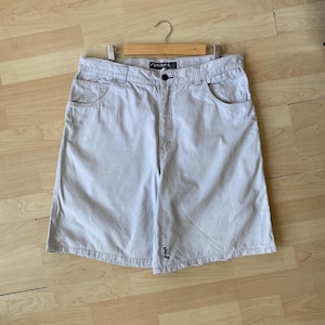 May include: Light gray shorts with a button closure and front and back pockets. The shorts are hanging on a wooden hanger. The brand name "Rip Curl" is visible on the waistband.