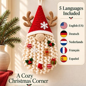 Könnte beinhalten: Ein gehäkelter Wandbehang in Form eines Wichtels mit roter Mütze, beiger Nase und langem cremefarbenem Bart, verziert mit kleinen Ornamenten wie Lebkuchenmann, Schneeflocke, Socke und Geschenk. Text liest 5 Languages Included und A Cozy Christmas Corner.