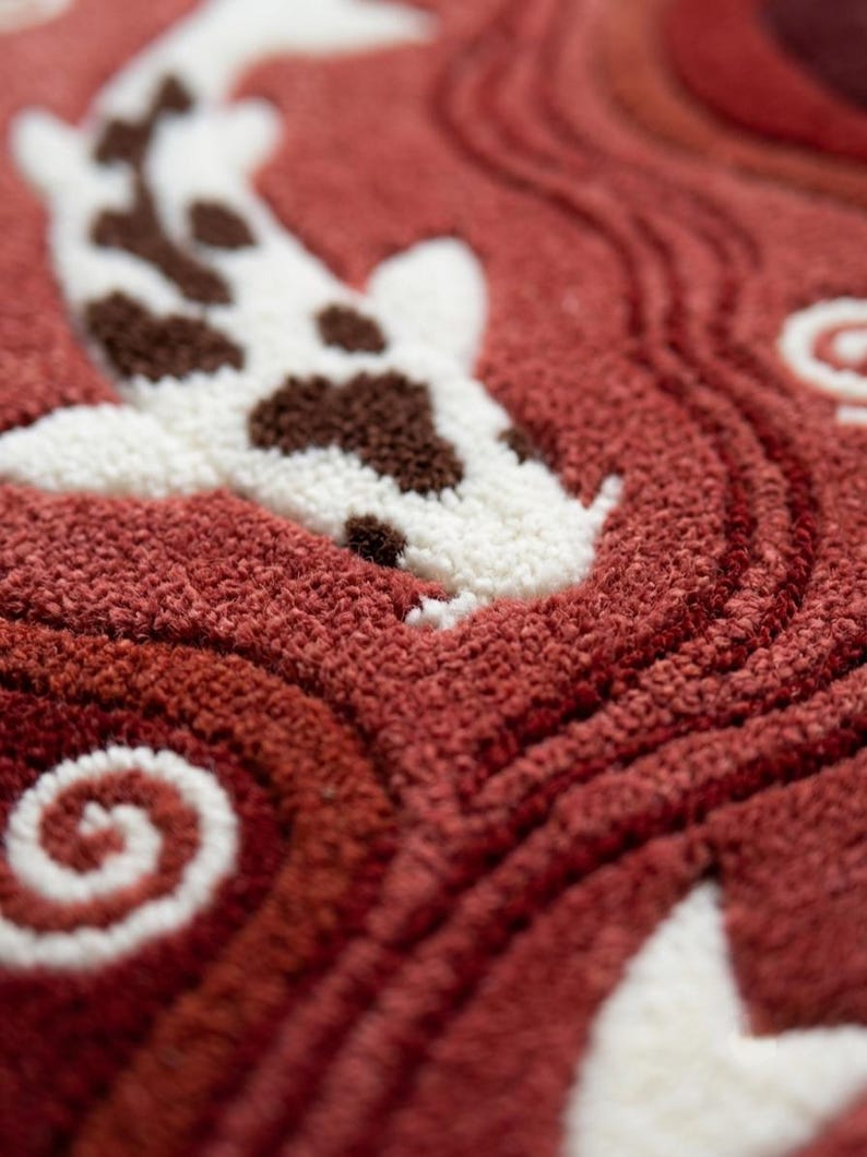 May include: A tufted textile piece featuring a white koi fish with brown spots swimming through a deep red background. The surface displays a textured, looped pile construction with swirling patterns that mimic water currents and ripples.