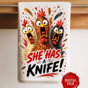 May include: A white waffle-textured kitchen towel featuring a colorful graphic of three wide-eyed, screaming chickens with red combs. Below the chickens, the text reads "SHE HAS A KNIFE!" in bold red and black lettering. A red circular "DIGITAL FILE" seal is present.