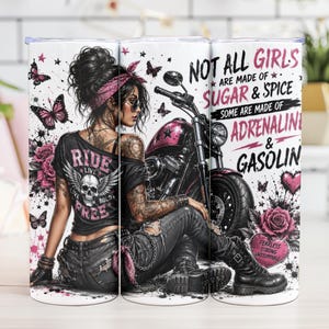 May include: A white tumbler with a biker theme. The design features a woman with tattoos, a motorcycle, butterflies, and roses. Text reads "NOT ALL GIRLS ARE MADE OF SUGAR & SPICE, SOME ARE MADE OF ADRENALINE & GASOLINE."
