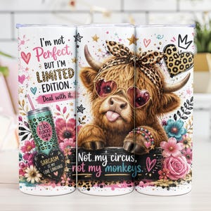 May include: A white tumbler featuring a Highland cow wearing heart-shaped sunglasses and a leopard print headband. The tumbler is decorated with floral accents and the phrases "I'm not perfect, but I'm limited edition" and "Not my circus, not my monkeys."