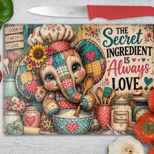 May include: A rectangular glass cutting board featuring a patchwork-style elephant wearing a chef hat, holding a wooden spoon over a bowl. The text reads: COOK WITH LOVE and THE SECRET INGREDIENT IS ALWAYS LOVE. Includes jars, kitchen tools, and flowers.