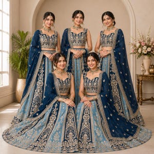 May include: Five women wearing matching blue and gold embroidered lehengas. The outfits include a crop top, long skirt, and a sheer shawl. The lehengas have intricate gold embroidery and are accessorized with matching jewelry.