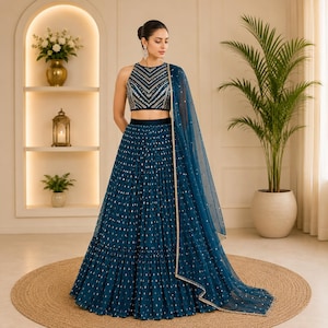 May include: A teal-colored formal dress with a matching sheer shawl. The dress features a high neckline and a pleated skirt with gold accents. The bodice is embellished with intricate silver and gold embroidery. The ensemble is suitable for special occasions.