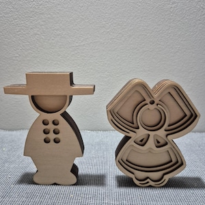 Peut inclure: Deux figurines en bois superposées, l'une en forme de personnage portant un chapeau à larges bords avec six découpes circulaires sur le torse, et l'autre en forme de personnage avec une grande coiffe et une robe, toutes deux en bois clair.