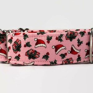 Puede incluir: Collar de perro rosa con un patr&oacute;n navide&ntilde;o con gorros de Pap&aacute; Noel, regalos y acebo.