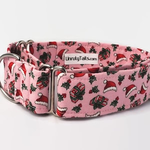 Puede incluir: Collar de perro rosa con un patr&oacute;n navide&ntilde;o de regalos, acebo y gorros de Pap&aacute; Noel. El collar tiene herrajes plateados y el texto "UnrulyTails.com" est&aacute; impreso en el collar.