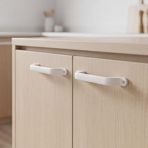 May include: Two matte white cabinet handles mounted horizontally on light-toned wood grain cabinet doors. Each handle features a simple, curved design with visible screw holes at both ends, providing a clean and functional aesthetic for cabinetry.