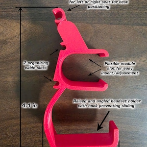 May include: A red headset holder with an angled clip and a raised, angled holder with a hook. It has two cable slots and a flexible module slot. The holder measures 4.1 inches high and 2.3 inches wide.