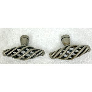 May include: Two silver-toned metal cabinet knobs featuring a horizontal, elongated, twisted cage design. Each knob has a central mounting post with a smooth, rounded base and a spiraling, open-work metal structure that forms a decorative handle.