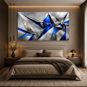 May include: A large rectangular wall art piece featuring a geometric abstract composition of metallic silver and deep blue triangular shapes. The surface displays a mix of smooth, reflective finishes and textured, brushed metal patterns.