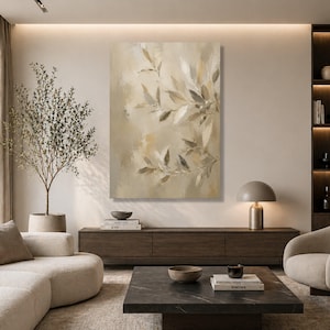 May include: Abstract canvas art in neutral tones of beige, brown, and grey. The artwork shows stylized leaves and branches, creating a calming, natural aesthetic. The painting is displayed in a modern living room setting.