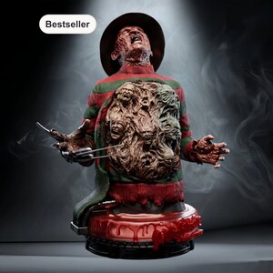 May include: A detailed bust of a horror movie character, with a scarred face, a brown fedora, and a red and green striped sweater. The chest area reveals sculpted faces. The figure has metal clawed fingers and is set on a bloody base.