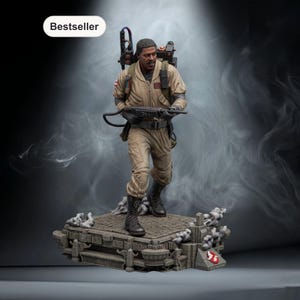 May include: A detailed figurine of a Ghostbuster in a tan jumpsuit, holding a proton pack and a weapon. The figure stands on a detailed base with the Ghostbusters logo. The word "Bestseller" is in a white oval in the upper left corner.