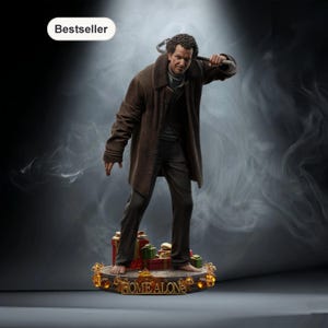 May include: A detailed figurine of a man in a brown coat holding a metal tool, standing on a base with the words "HOME ALONE". The base is decorated with Christmas presents and lights. The word "Bestseller" is in the top left corner.