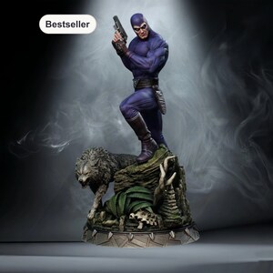 May include: A detailed statue of a costumed figure in a purple suit and mask, holding a gun. The figure stands on a rocky base with a wolf and foliage. The word "Bestseller" is in a white oval.