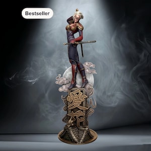 Puede incluir: Figura detallada de una guerrera con una espada, de pie sobre una base decorativa. La figura viste un atuendo azul oscuro y rojo, con el pelo rubio. La base presenta elementos de diseño de inspiración asiática y la palabra "Bestseller".