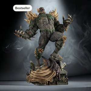 Peut inclure: Statue détaillée d'une figure monstrueuse avec une peau grise, des accents verts et des griffes acérées. La figurine est posée de manière dynamique, avec une cape déchirée et une base aux détails complexes. Le mot "Bestseller" est dans un ovale blanc en haut à gauche.