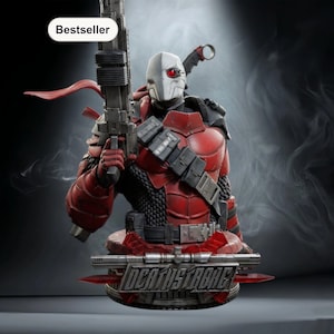 May include: A Deathstroke bust figurine, featuring a red and black armored design with a white and gray mask. The figurine holds a large gun and has the word "Bestseller" in the top left corner. The base of the bust has the name "Deathstroke" in silver lettering.