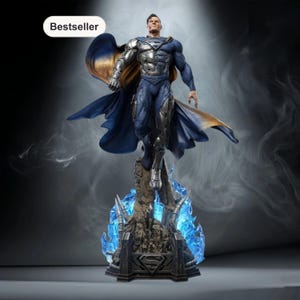 Può includere: Statua di Superman in posa dinamica, con un costume blu e argento e un mantello svolazzante. La statua è montata su una base dettagliata con effetti di energia blu. La parola "Bestseller" è nell'angolo in alto a sinistra.