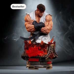 Op de afbeelding: Gedetailleerde buste van een gespierd personage uit Street Fighter, gekleed in een witte gi, zwarte gordel en polsbanden. De figuur heeft een rode hoofdband en poseert met gekruiste armen. De basis heeft het Street Fighter-logo in rood, met vlammen en een pagode-achtig ontwerp.