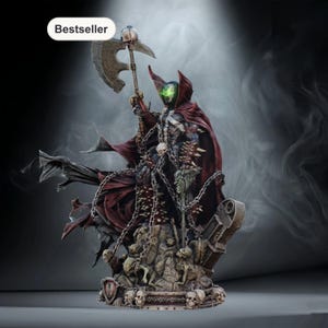 Könnte beinhalten: Detaillierte Statue der Comicfigur Spawn, die eine Axt hält und in einen roten Umhang gehüllt ist. Die Figur ist mit Ketten und Totenköpfen geschmückt, auf einem Sockel mit Skelettfiguren. Das Wort "Bestseller" befindet sich in einem weißen Oval.