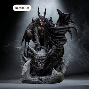 Puede incluir: Estatua detallada de Batman en cuclillas, con capa y capucha ondeantes. La figura es de color gris oscuro y negro, posada sobre una base de gárgola de piedra con una calavera. La palabra "Bestseller" está en un óvalo blanco.