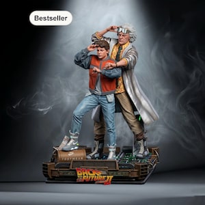 Könnte beinhalten: Detaillierte Statue mit Figuren aus Zurück in die Zukunft II. Die Statue zeigt Marty McFly und Doc Brown auf einer Zeitmaschinenbasis. Die Basis trägt den Text "Back to the Future II". Die Statue ist ein Bestseller.