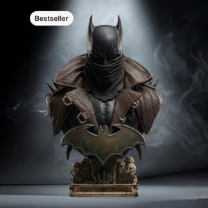 May include: A Batman bust statue with a black cowl and a brown leather-like jacket. The statue features a bat symbol and a base with skulls. The word "Bestseller" is in a white box in the upper left corner.