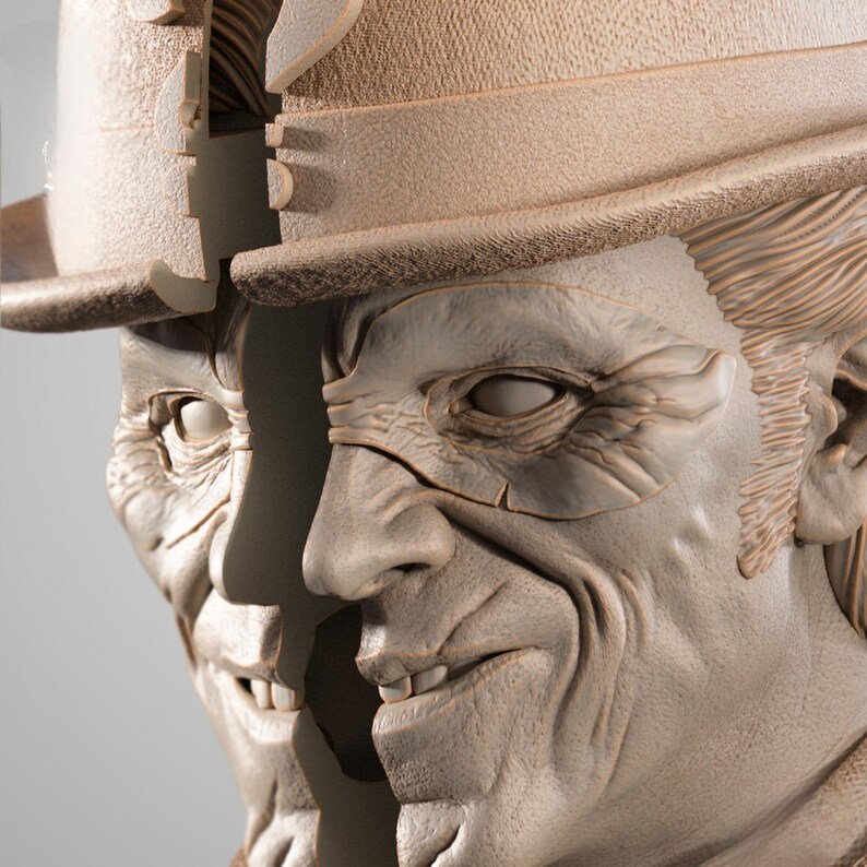 May include: A detailed sculpture of a man's face, split in two, with a hat and eye mask. The sculpture is a light beige color, with visible wrinkles and fine details. The man is smiling, revealing his teeth.