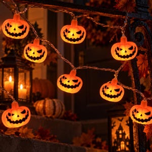 May include: A string of orange pumpkin-shaped LED lights, each featuring a carved jack-o'-lantern face with black eyes and a jagged mouth. The lights are connected by a thin, clear wire, emitting a warm, glowing light from within each pumpkin.