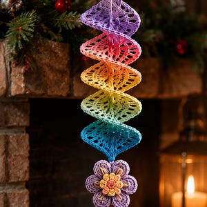 May include: A hanging crochet ornament featuring a spiral design in a rainbow gradient of purple, pink, orange, yellow, green, and blue. The spiral is topped with three small wooden beads and ends with a crocheted flower and a multi-colored tassel.