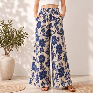 Puede incluir: Pantalones de pierna ancha con base color crema y un llamativo estampado floral azul. Estos pantalones cuentan con una cintura alta elástica y dos bolsillos laterales, ofreciendo una silueta holgada y fluida hasta los tobillos.