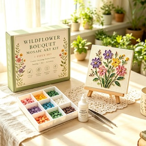 Peut inclure: Un kit d'art mosaïque Wildflower Bouquet dans une boîte verte, comprenant une toile carrée sur un chevalet en bois avec un motif floral. Inclut un plateau blanc à neuf compartiments rempli de carreaux colorés, de la colle et une pince en métal.