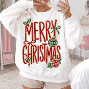 Puede incluir: Una sudadera blanca de manga larga con un estampado gráfico que incluye el texto rojo Merry Christmas. El diseño presenta bayas de acebo verdes, un bastón de caramelo y dos adornos redondos con patrones rojos y verdes, delineados en oro.