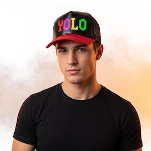 Peut inclure: Une casquette de baseball noire avec une visière rouge et un arrière en filet. Le panneau avant affiche le mot YOLO illuminé dans un style matriciel avec des lumières LED rouges, roses, jaunes et vertes sur une surface noire lisse.
