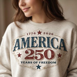Pu&ograve; includere: Felpa beige con grafica invecchiata che celebra il 250&deg; anniversario dell'America. Il design presenta la parola "AMERICA" in blu, il numero "250" in rosso e il testo "YEARS OF FREEDOM". Stelle e gli anni 1776 e 2026 completano il design.