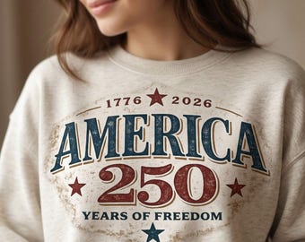 Può includere: Felpa beige con grafica invecchiata che celebra il 250° anniversario dell'America. Il design presenta la parola "AMERICA" in blu, il numero "250" in rosso e il testo "YEARS OF FREEDOM". Stelle e gli anni 1776 e 2026 completano il design.