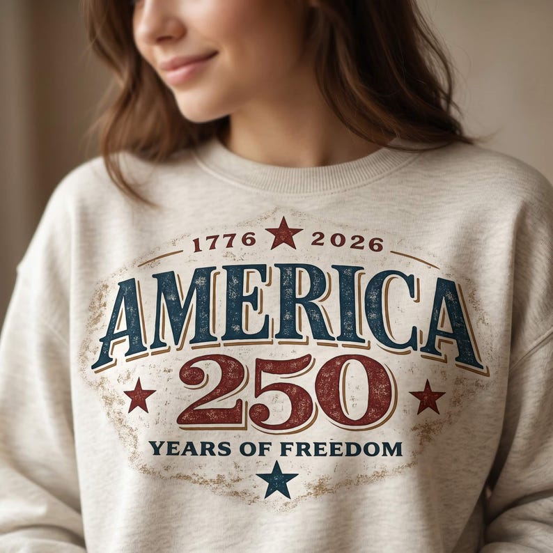 Pu&ograve; includere: Felpa beige con grafica invecchiata che celebra il 250&deg; anniversario dell'America. Il design presenta la parola "AMERICA" in blu, il numero "250" in rosso e il testo "YEARS OF FREEDOM". Stelle e gli anni 1776 e 2026 completano il design.
