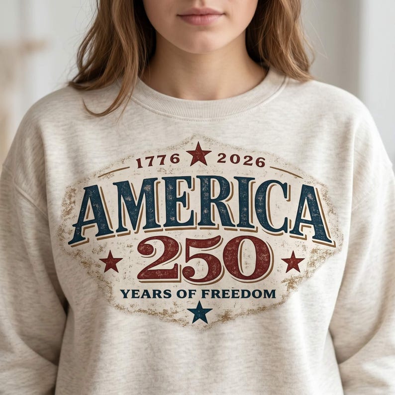 Pu&ograve; includere: Una felpa beige con una grafica invecchiata che celebra il 250&deg; anniversario dell'America. Il design presenta la parola "AMERICA" in blu navy, "250" in rosso e gli anni "1776" e "2026". &Egrave; incluso anche il testo "YEARS OF FREEDOM".