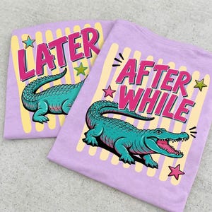 May include: Two light purple t-shirts with alligator graphics. One shirt says "LATER" in pink letters with a yellow background. The other says "AFTER WHILE" in pink letters with a yellow background. Both shirts have a teal alligator.