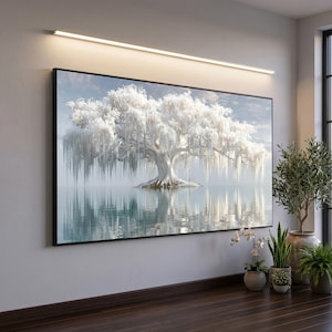 May include: A large rectangular wall art print featuring a white weeping willow tree centered in a calm body of water. The tree has long, drooping branches and is reflected in the water below. The scene is illuminated by a long, thin light fixture.