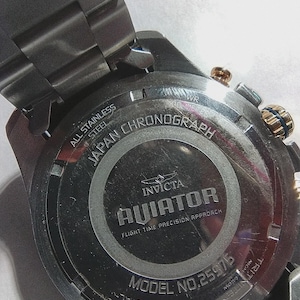 May include: Close-up of the back of a stainless steel Invicta Aviator chronograph watch. The watch features the text "All Stainless Steel", "Japan Chronograph", and "Aviator". The model number is 25975.