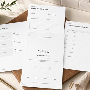 Puede incluir: Una colección de hojas de papel blanco con texto, incluyendo un "No Waste Kitchen Reset Kit" y un "7-Day No-Waste Kitchen Reset Plan". Los papeles están sobre una tabla de cortar de madera, con un bolígrafo dorado y una pequeña planta en una maceta de cerámica.