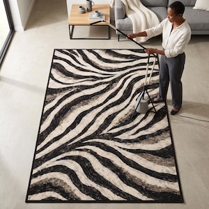 Peut inclure: Un tapis rectangulaire présentant un motif de rayures zébrées à fort contraste dans des tons de noir, crème et gris foncé. Le tapis possède une bordure noire unie encadrant les lignes organiques et fluides sur toute sa surface.